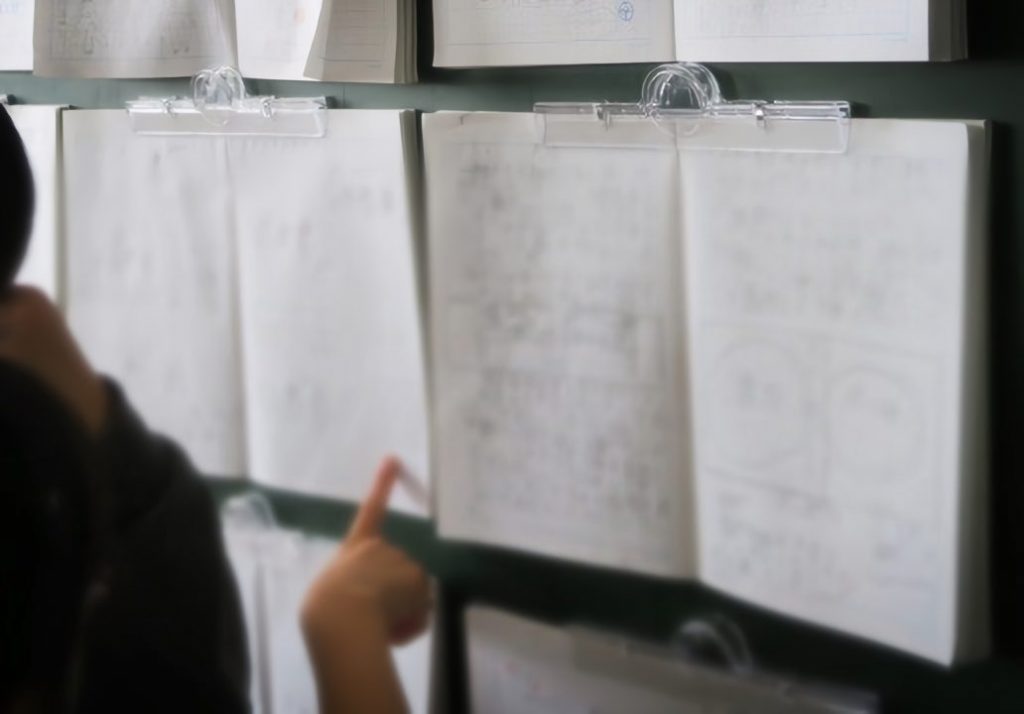 マグネットクリップを使って教室の後方に、家庭学習ノートをそのまま掲示。子供たちが互いのノートを見合うことで、学び合いや感化が促される。