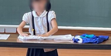 お手伝いをしていた服たたみを、クラスのみんなの前で実演する女児