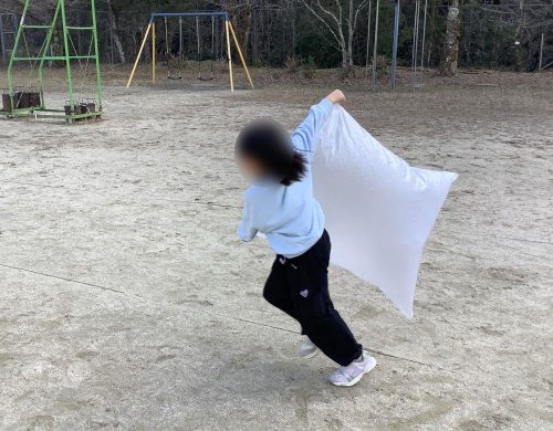 ポリ袋で風を捕まえる子供