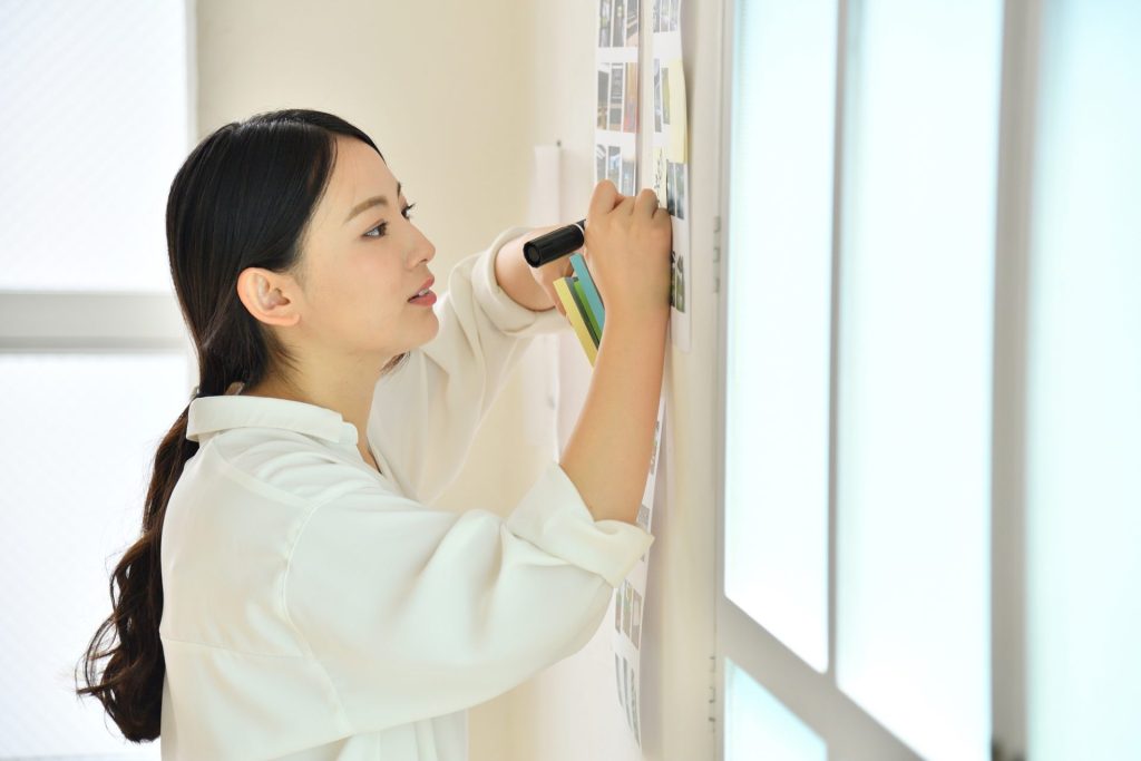 壁のポスターに何かを書き込んでいる女性