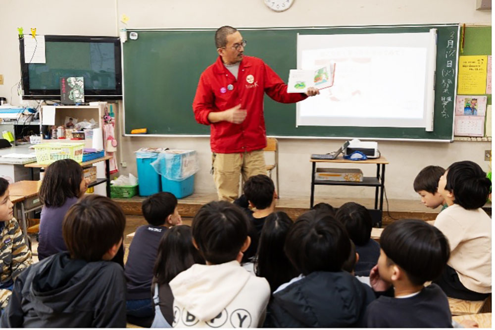 絵本を読み聞かせる大窪教諭と、中央のスペースで聞く子どもたち。