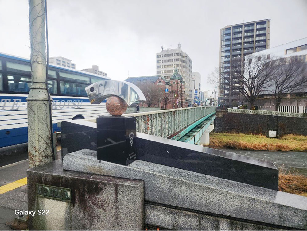 写真①は中津川に架かる橋に取り付けられているモニュメントです。盛岡市青年会議所が寄贈したものです。また、このモニュメントの近くには、写真②のような看板が設置されています。