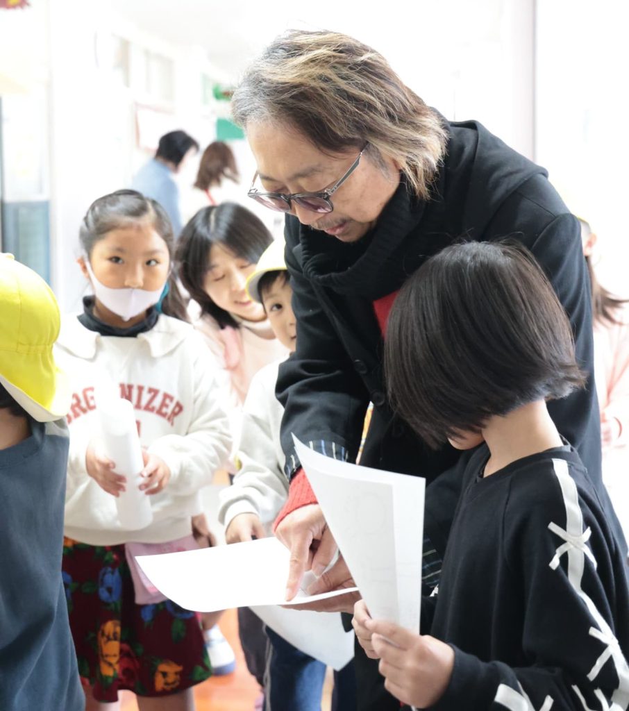 小学生に、この日の遊びのルールを教えてもらっている大豆生田啓友先生。