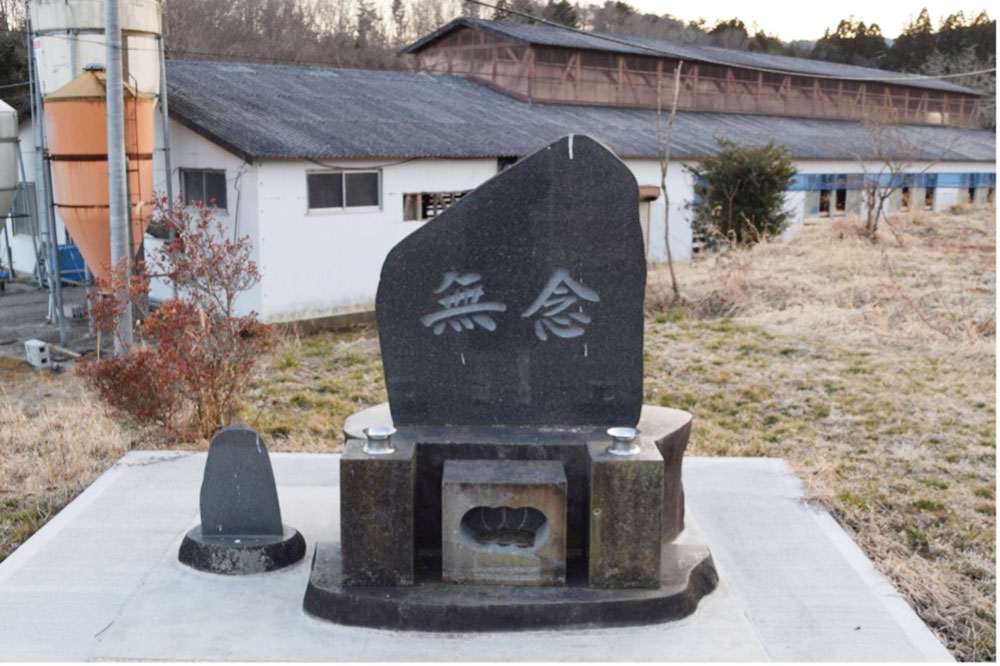 写真③半杭さんが被災後に牛舎のそばに建てた「無念」と書かれた石碑