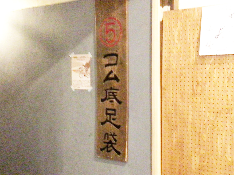 「兎に角」の壁に飾られた「ゴム底足袋」の看板