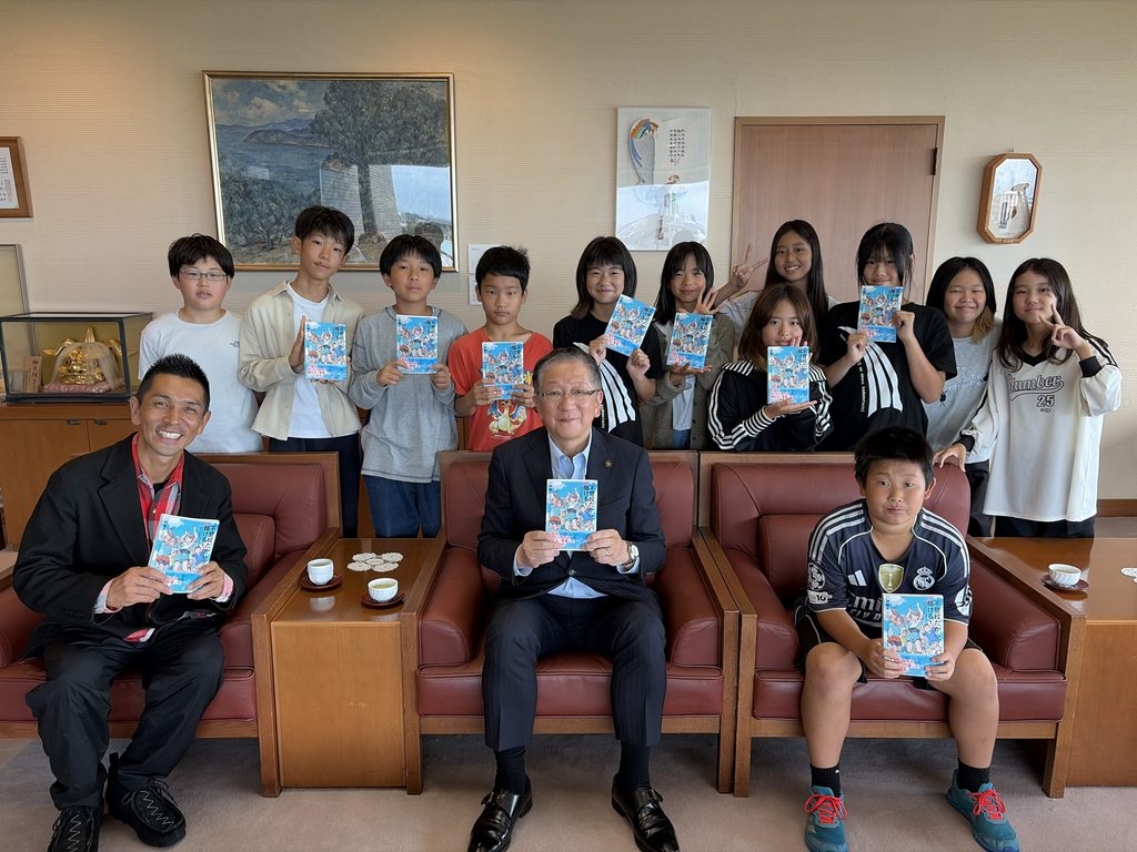 『不登校だから輝ける！花まるエレメンタリースクールの挑戦』を手に小美濃安弘市長(中央)と子どもたち